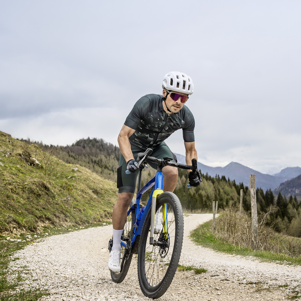 Uomo in sella a una bici gravel su una strada rurale